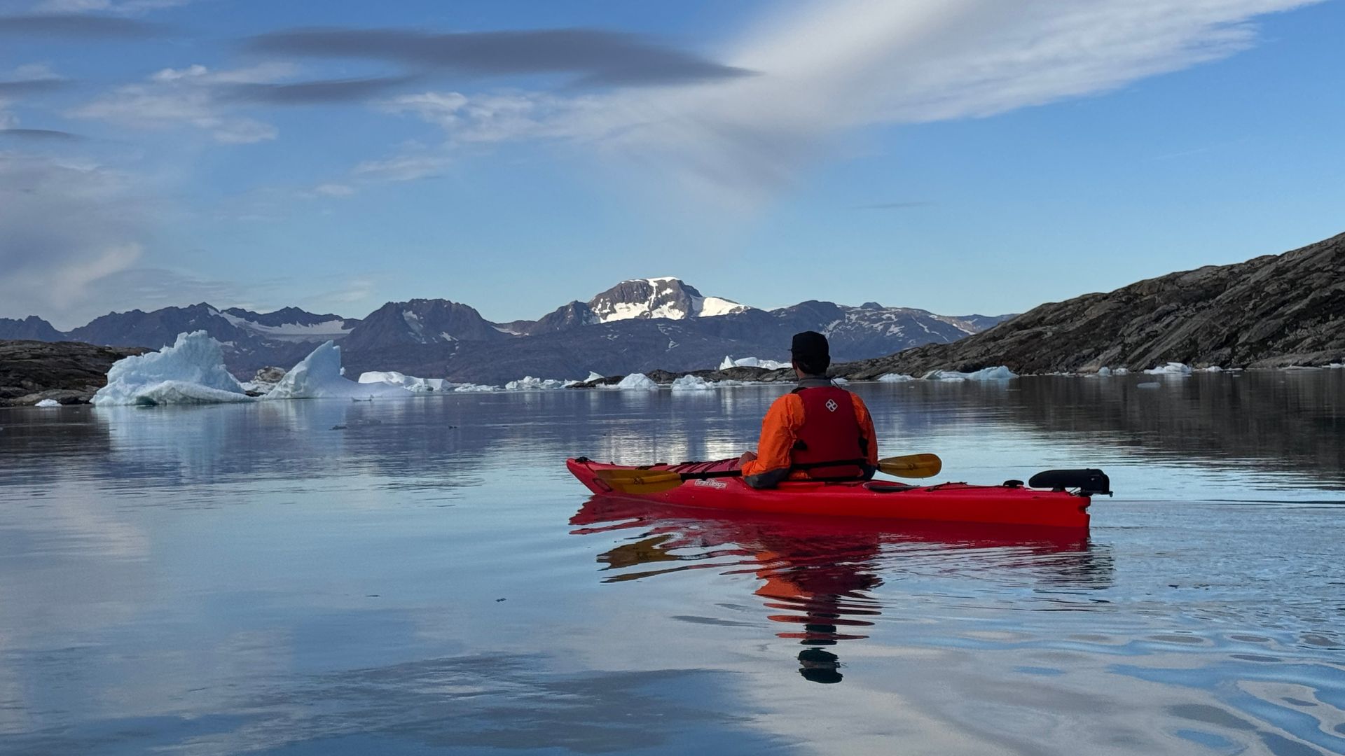 Man kayaking near icebergs in Greenland