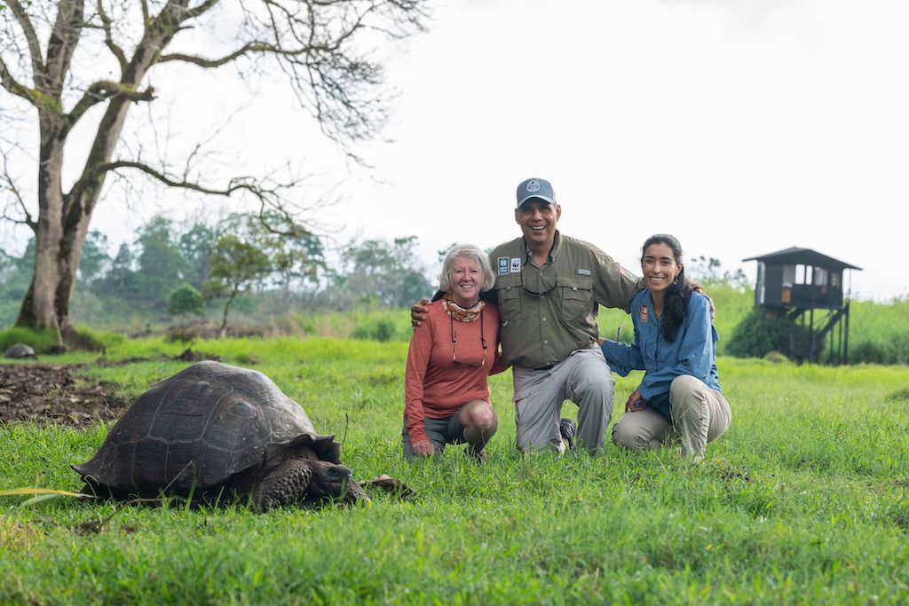 Nat Hab travelers and Expedition Leader in the Galapagos with a giant tortoise.